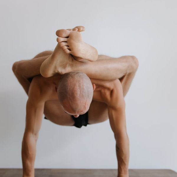 Person practicing a yoga balancing pose against a minimalist background.